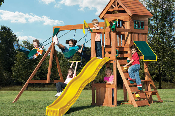 Little children happily playing on a wooden playground set in the summer