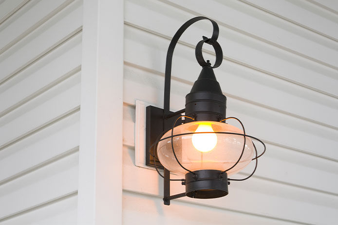 Black outdoor light fixture on the corner of a house