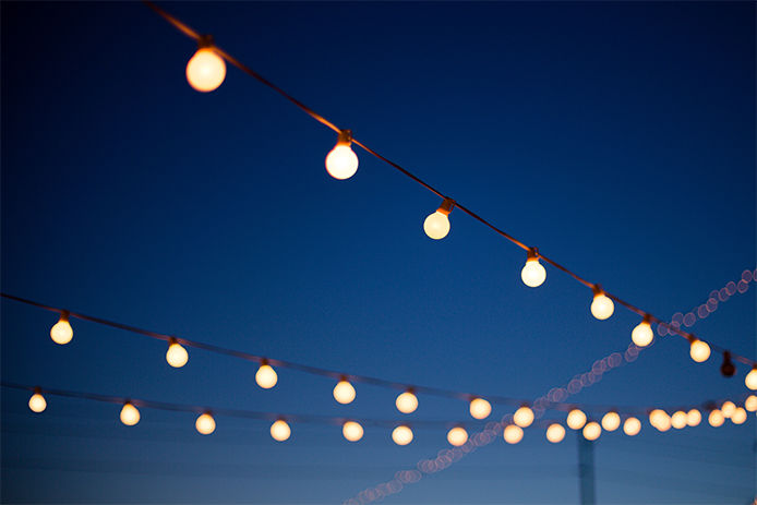 Patio string lights hanging from wooden poles in a backyard on a dark summer night
