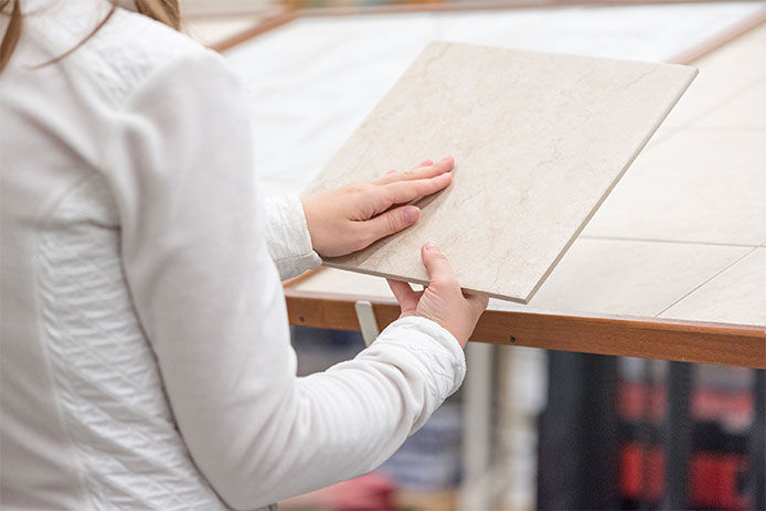 Woman looking at a piece of tile in-store