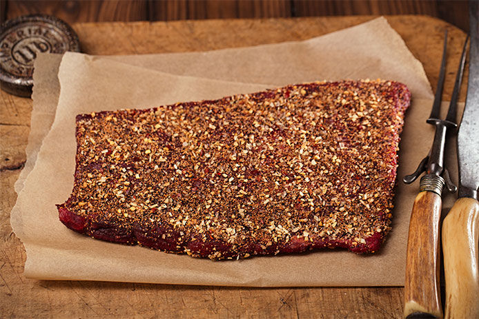 Slab of meat on a wooden cutting board covered in a meat rub