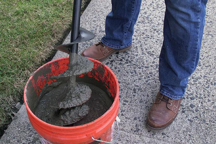 Mixing concrete in a red bucket