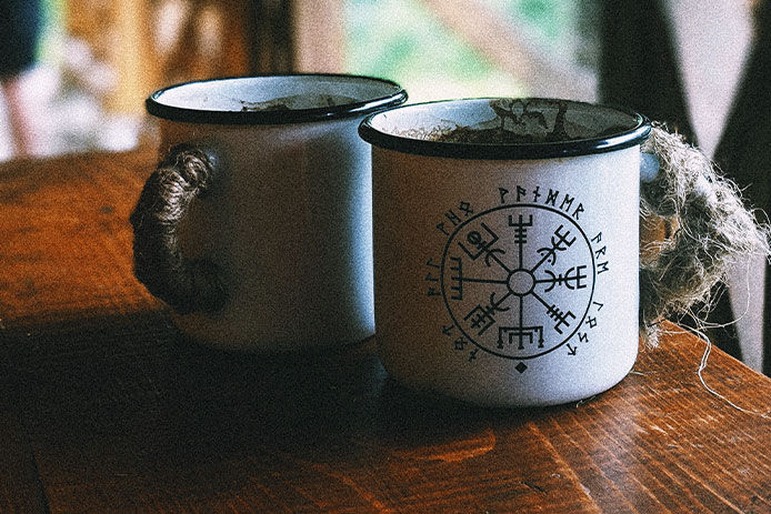 Two tin migs on a wooden table