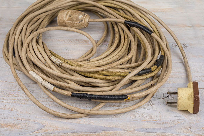 Old worn out extension cord with black electrical tape