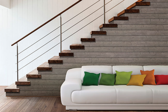 A beauiful open concept living room with gray shiplap framing the side of a stair case. There is a beautiful white sofa with color pillow in from of the stair case.