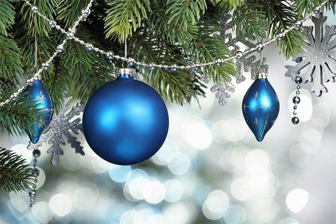 a close up of blue Christmas ornaments hanging from a Christmas tree