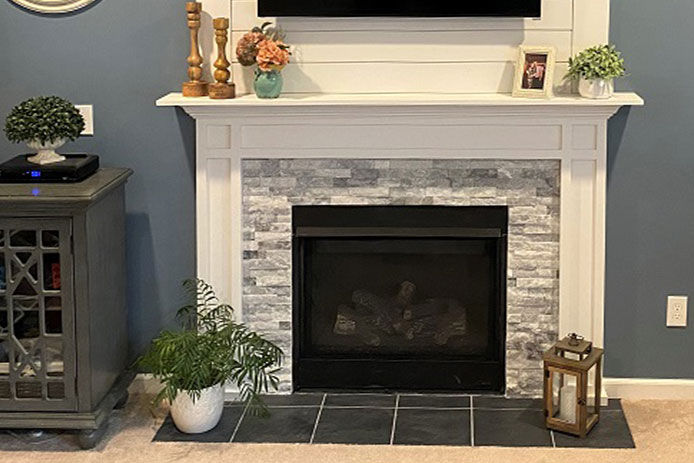 Large living room wall with a moderned tiled fireplace. There are decorative accents surrounding the fireplace including a lantern and a plant.