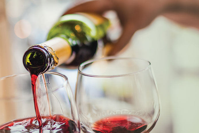 Person pouring wine into wine glasses