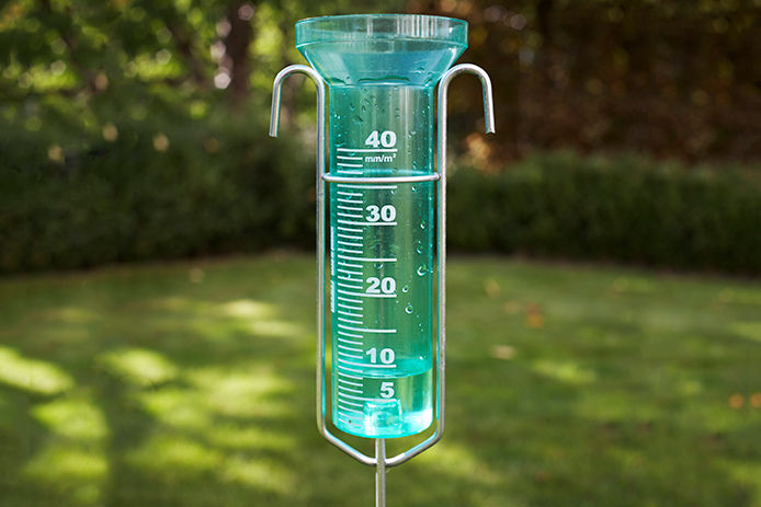 Green rain gauge set in outside garden