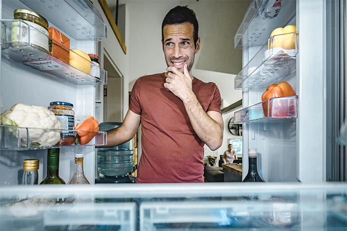 Man with the looking inside the fridge with both door open