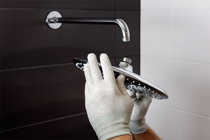 Person wearing gloves taking the shower head off