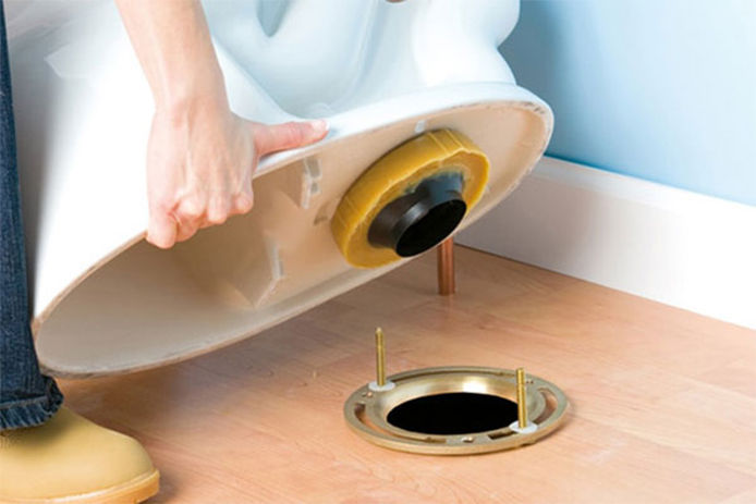 An image of a professional plumber installing a new toilet in a bathroom 