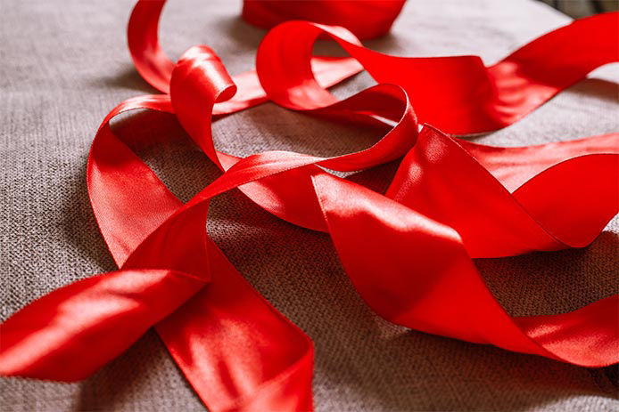 red ribbon on a beige couch ready to be hung as decoration of a Christmas tree