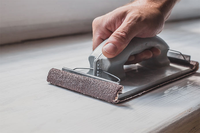 Person using a handheld sander, close-up