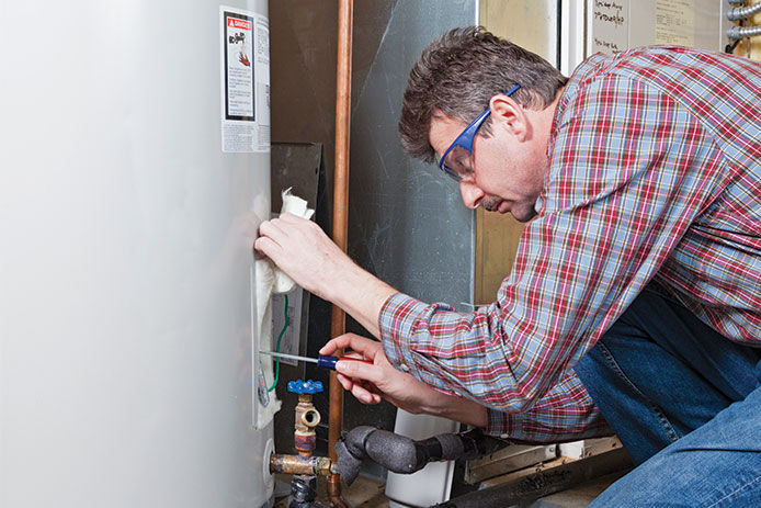 Man with safety glasses on with a screwdriver taking a look at sump pump