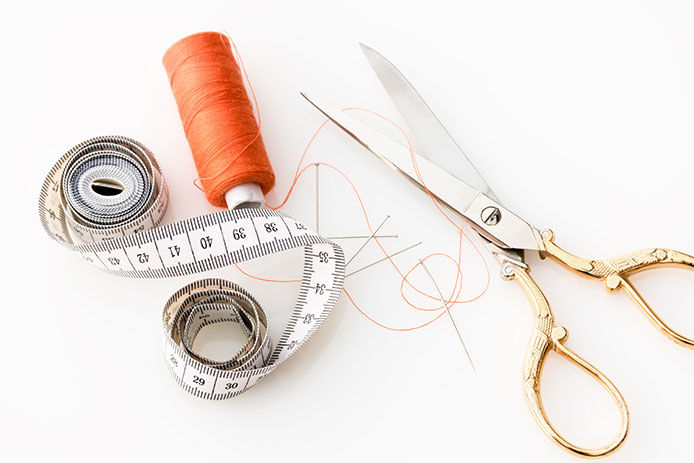A pair of scissors, sewing thread, and a measuring tape