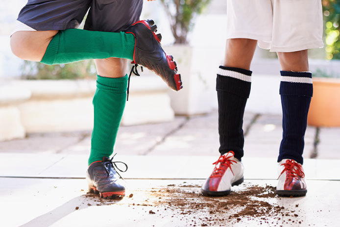 two young kids with muddy cleats after playing a soccer game. 