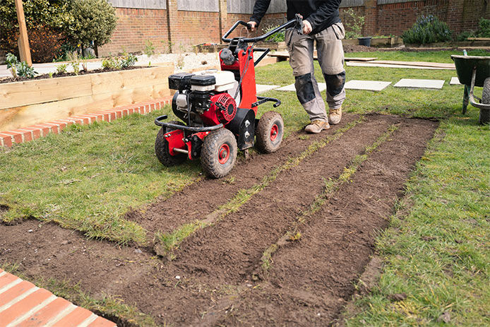 A man using a gas powered sod remover to remove grass from his lawn