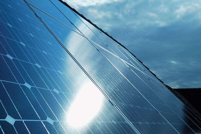 Row of blue and black solar panels reflecting the sunlight off of the bottom left corner