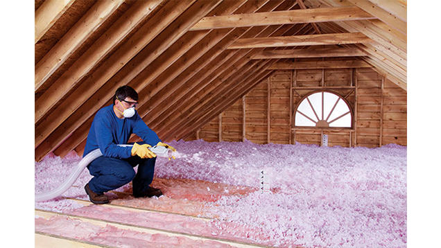 Man wearing PPE and spraying insulation in an attic