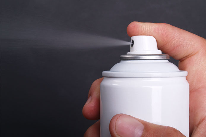 Person spraying an aerosol spray can