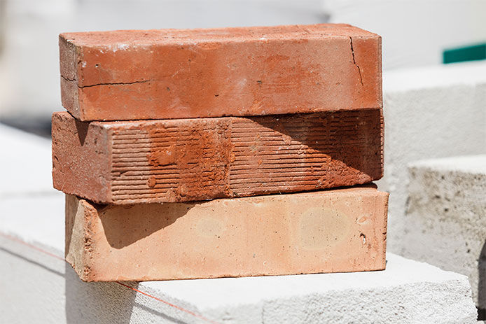 Stack of orange bricks on construction site. Renovation, building objects and details concept.