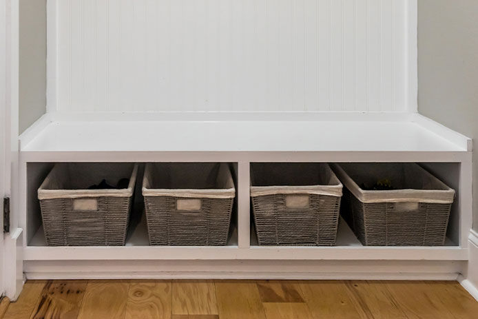 lower storage area in a mudroom with woven baskets used for holding smaller items 