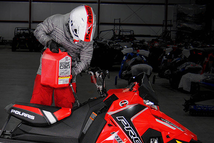 A person fueling their snowmobile with a SureCan gas can