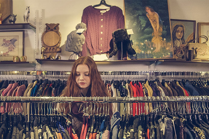 A teenage girl browsing the clothes rack at a thrift store