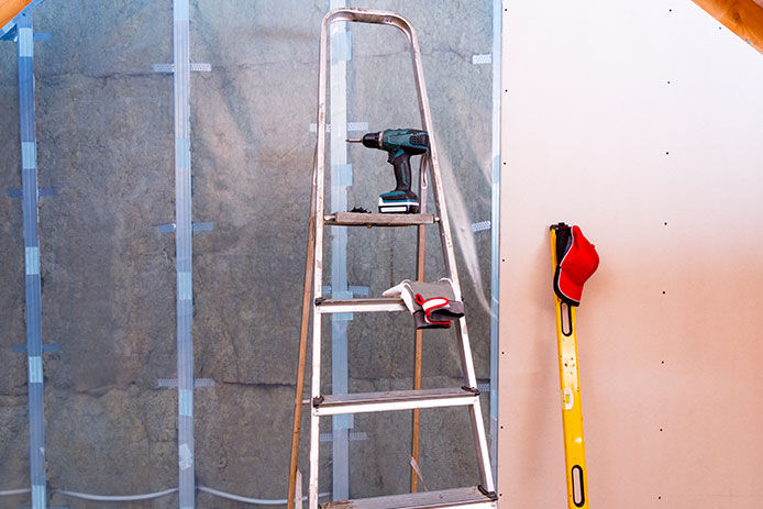 Ladder, power drill, level, and safety gloves