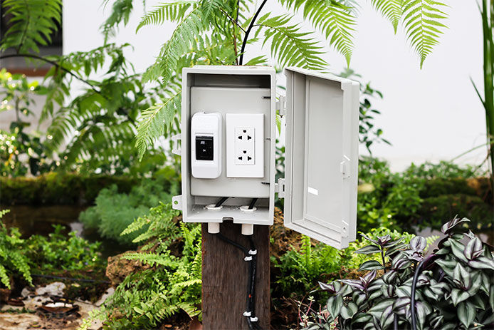 A transformer box wired in a residential backyard used for adding wired lighting into the landscaping 