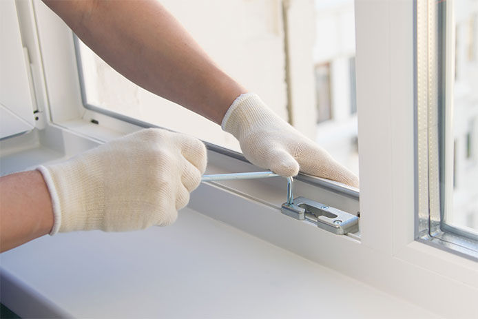 Man installing window locks to further reinforce them from intruders