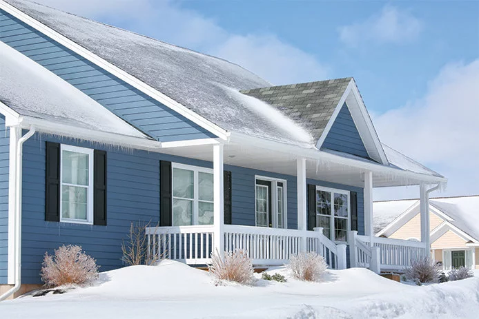 The outside of a blue house during the winter with snow on the ground