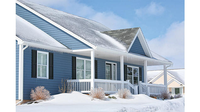 The outside of a blue house during the winter with snow on the ground