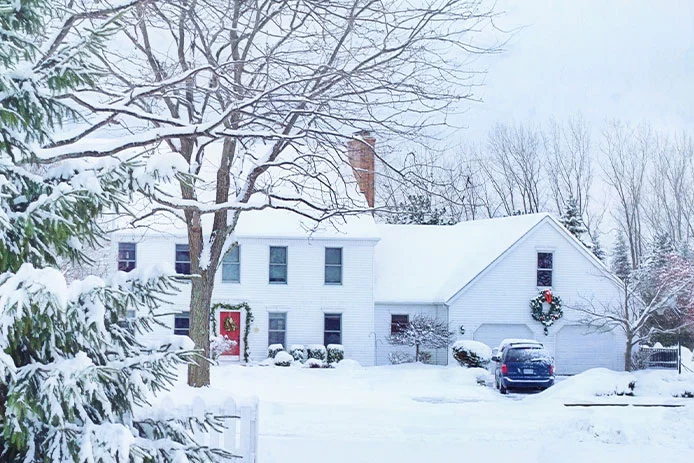 The outside of a white house during the winter with snow on the ground