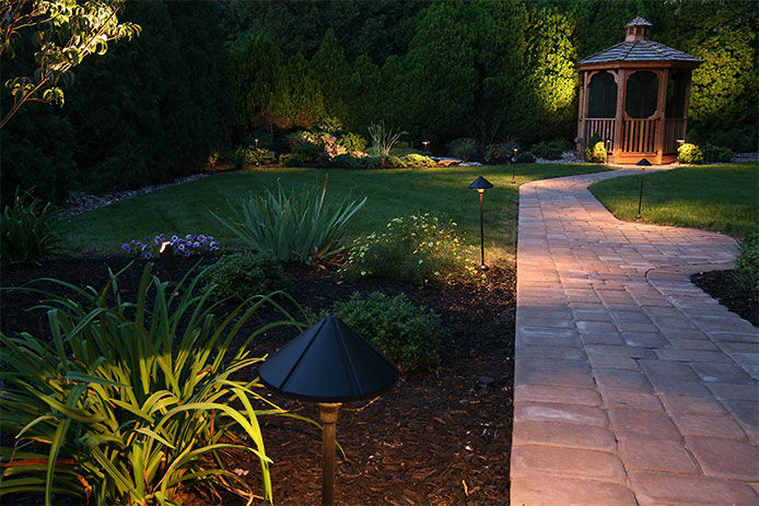 A residential walkway in the evening lit up by wired in landscaping lights 