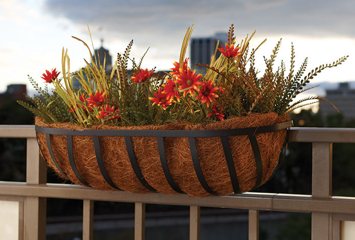 A flower planter haning from a railing