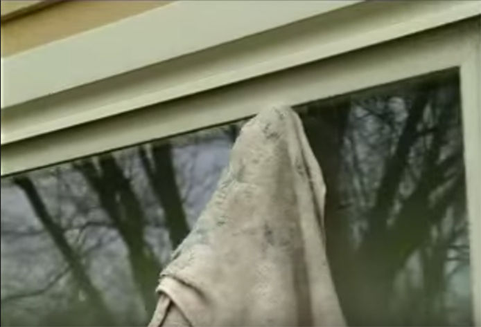 A person drying a window with a cloth