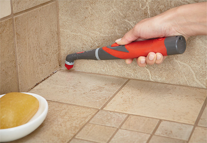A person scrubbing tile grout
