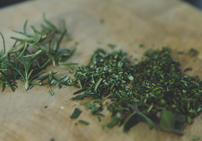 Chopped up herbs on a wooden cutting board