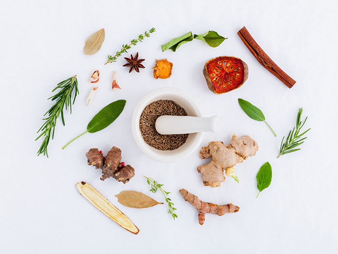 Different herbs laid out on a white background, overhead shot