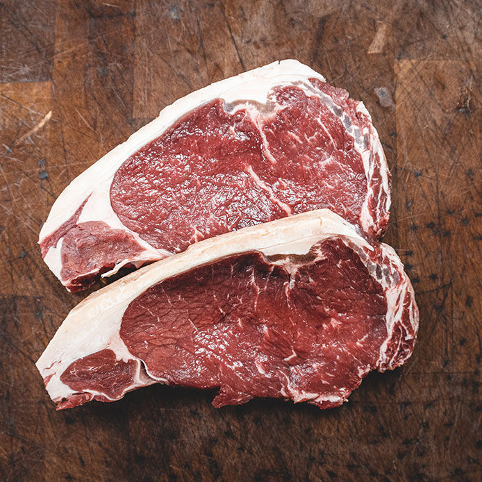 Two stunning mouth-watering marbled sirloin steak on a rustic butcher block. 