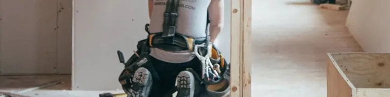 Man crouched working on putting in drywall