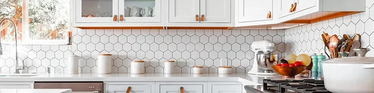 Brightly lit kitchen with white cabinets and backsplash tile