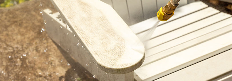 Cleaning a white patio chair with a power washer