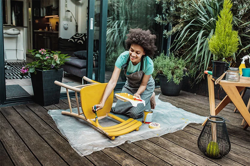 Woman painting a chair yellow 