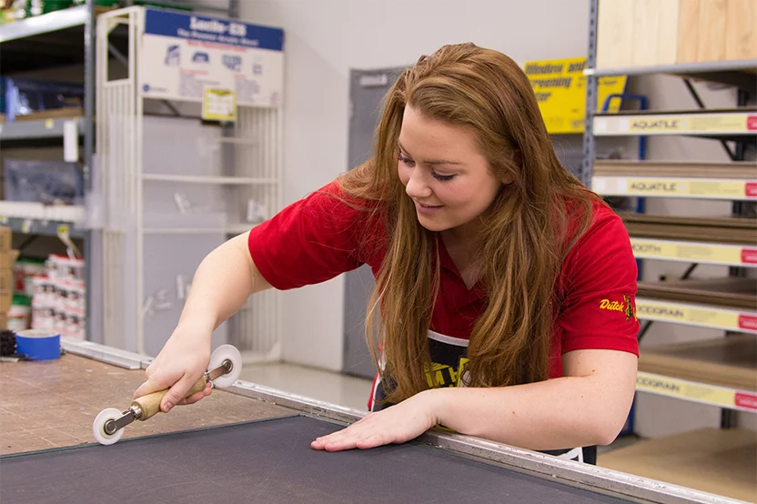 employee fixing a window screen