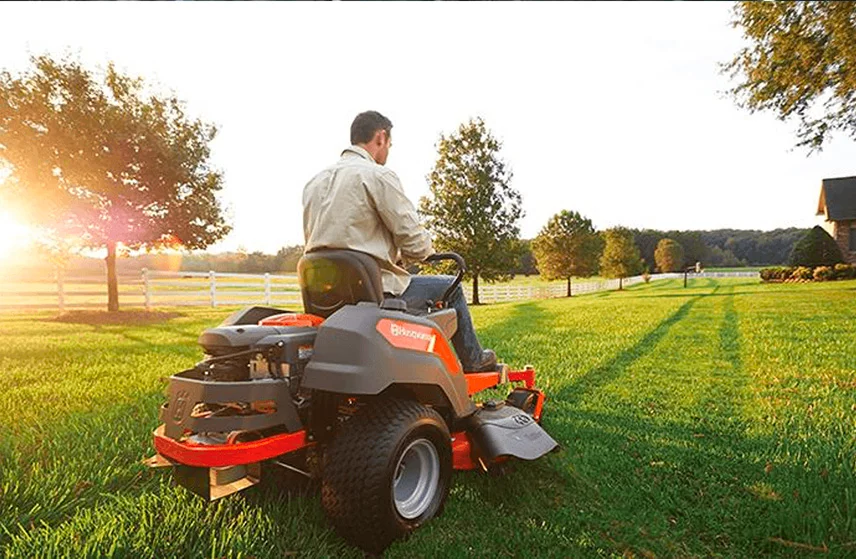 person cutting grass with husqvarna mower