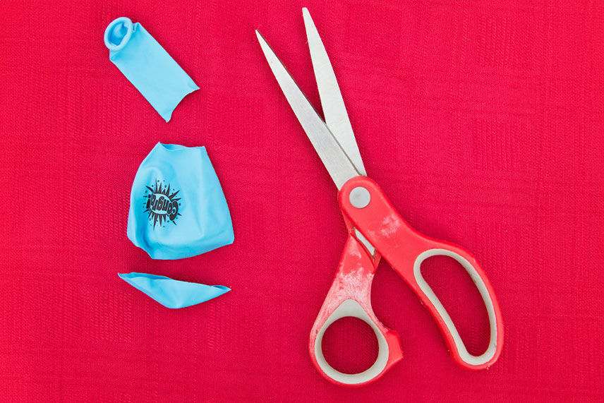 Scissor and balloon sitting on a red background