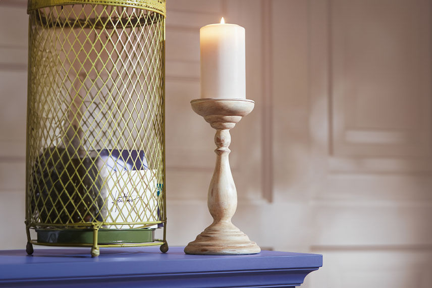 Ivory white candle stick sitting on a colonial blue mantel